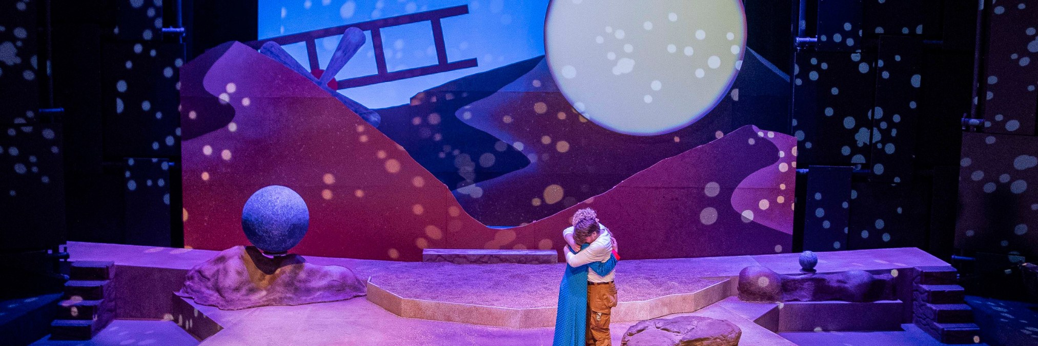 Magical set with a full moon, a desert, and a crashed plane with the Little Prince and the Aviator hugging in the foreground
