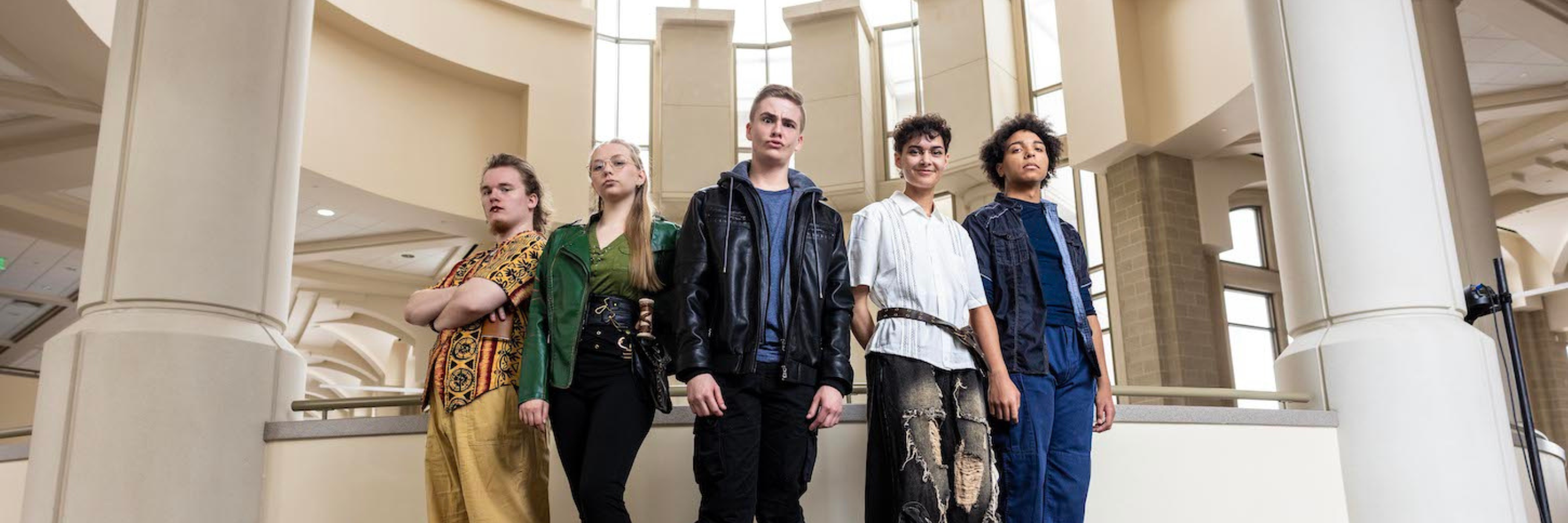 Five students stand together in front of the performing arts pillars