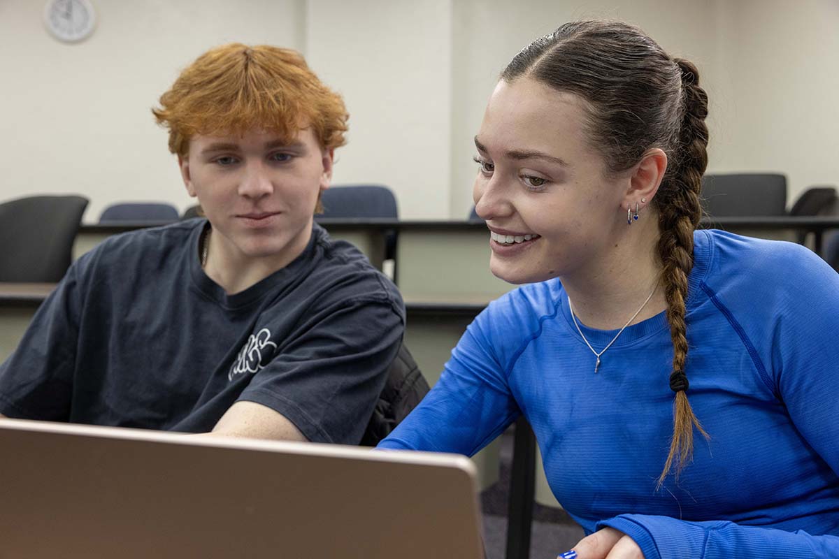 Two students collaborating in front of a laptop