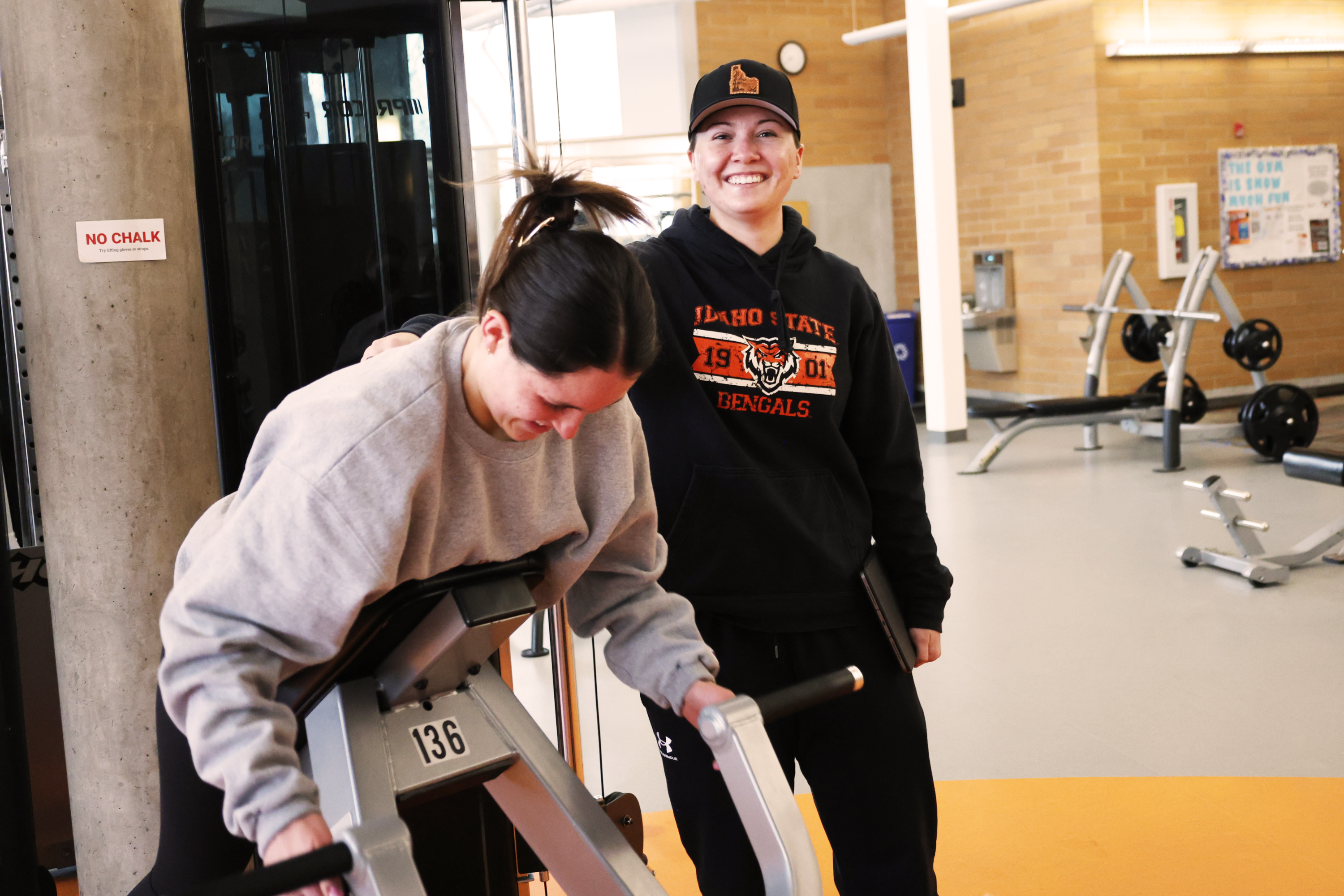 Fitness trainer with student using gym equipment