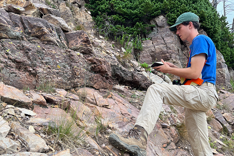 Zachary Ellia, graduate student at Idaho State University, examines an exposure of the Great Unconformity in the Teton Range.