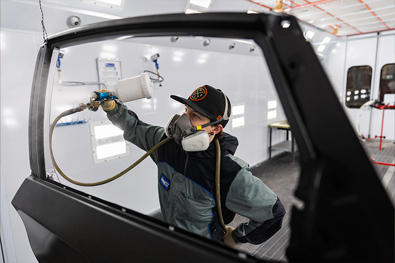 Automotive Collision Repair and Refinishing student painting a car door