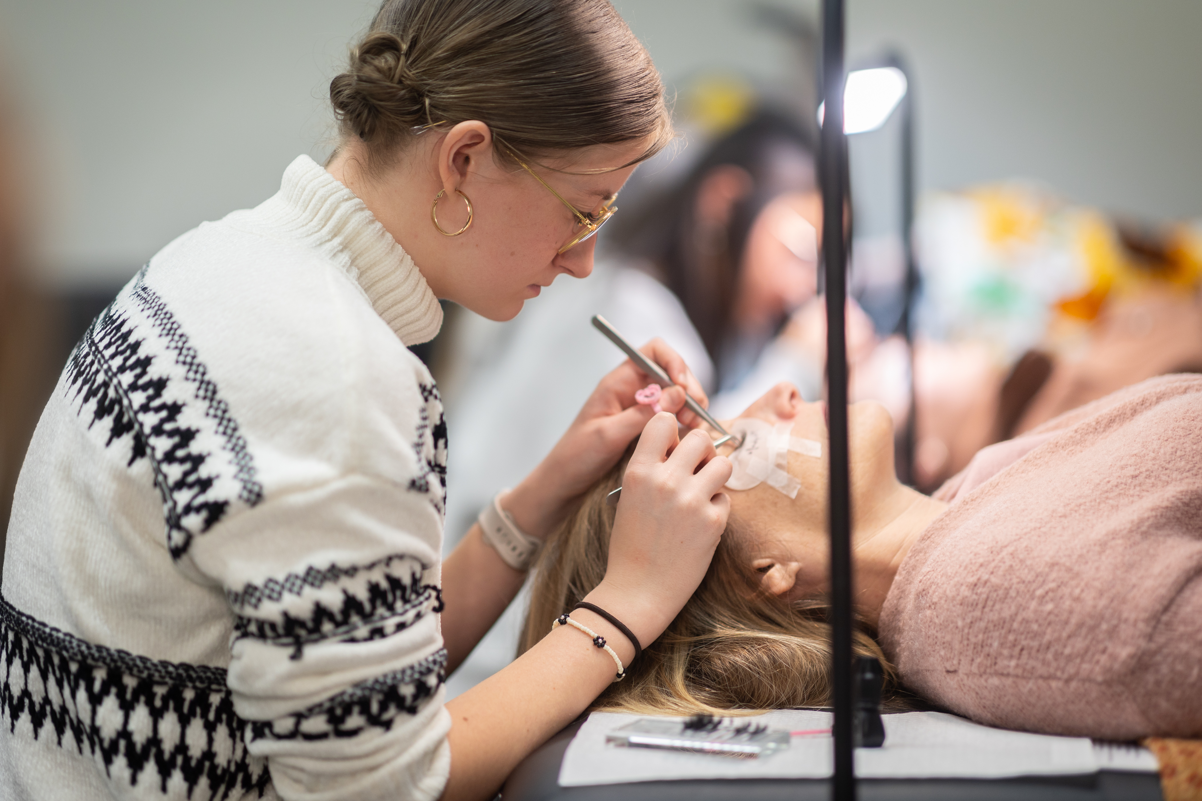 Cosmetology student appling eyelashs on a customer in the ISU Salon