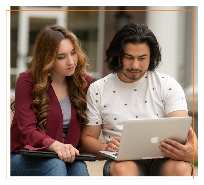 Two students sitting together review information on a laptop, representing exploration of tuition costs and financial aid options for college.