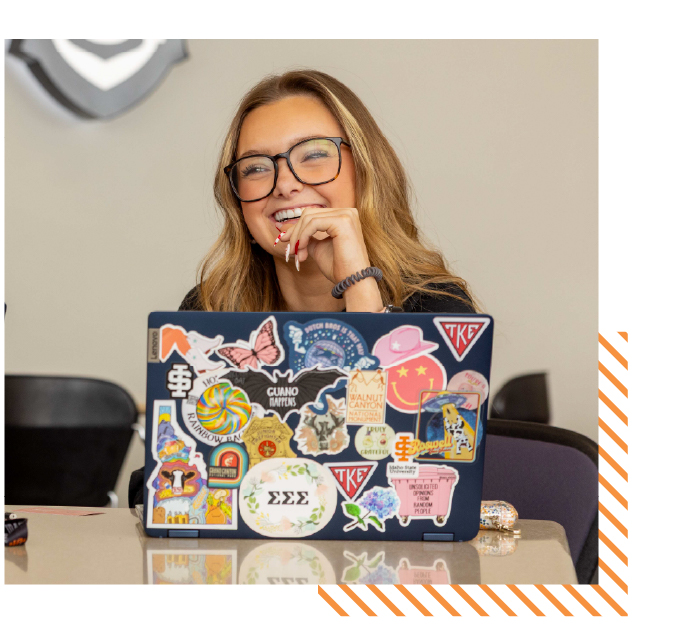 Student smiling while studying on a laptop in a classroom, representing high school students earning college credit through ISU’s Early College program.