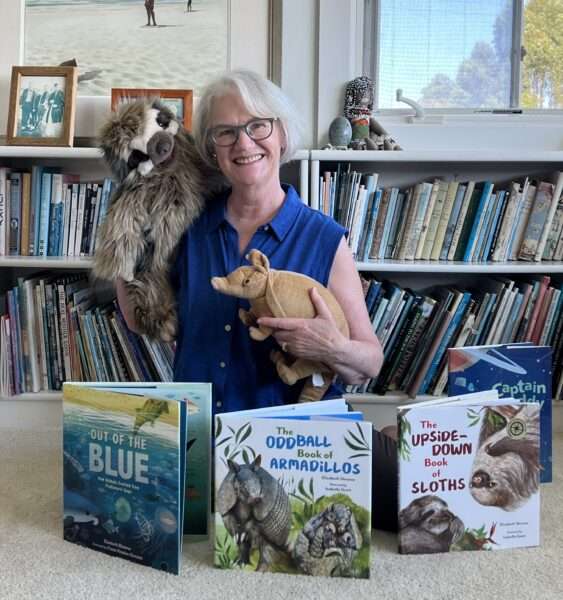 Elizabeth Shreeve posing with her children's books and associated stuffed animals
